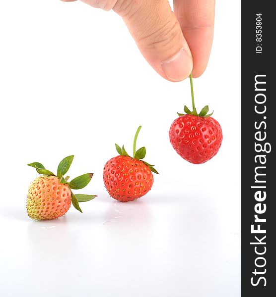 The hand is taking the strawberry. The hand is taking the strawberry