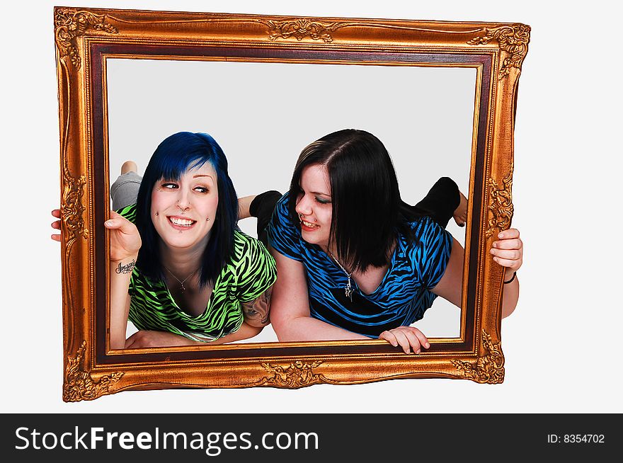 Two young girls laying on the floor and looking trough a picture frame over white background. Two young girls laying on the floor and looking trough a picture frame over white background.