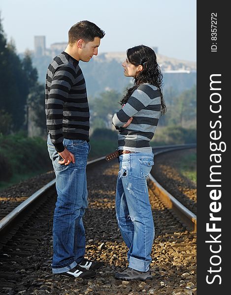 Young couple looking each other on railway tracks. Young couple looking each other on railway tracks