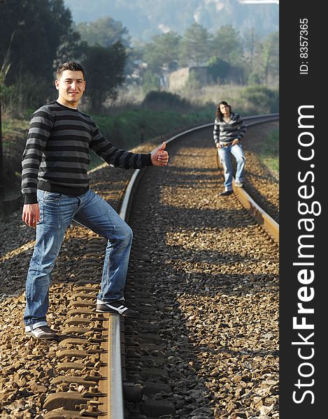 Young couple walking and looking for the train on the railway tracks. Young couple walking and looking for the train on the railway tracks