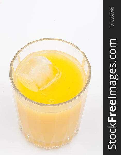 Orange juice in a glass containing ice cubes, shot against a white backdrop