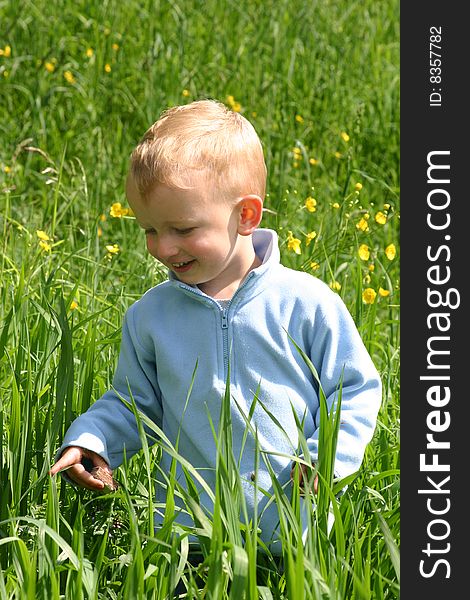 Cute toddler boy sitting amid spring grass and flowers. Cute toddler boy sitting amid spring grass and flowers