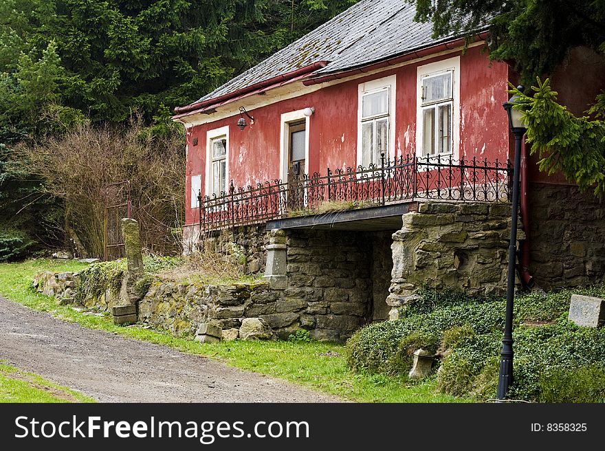 Old red impaired house with white windows and iron rail on the stone wall. Old red impaired house with white windows and iron rail on the stone wall