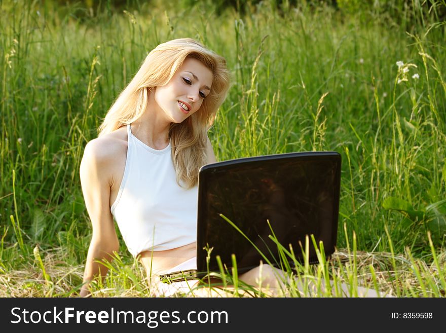 Pretty blonde with a laptop in grass. Pretty blonde with a laptop in grass
