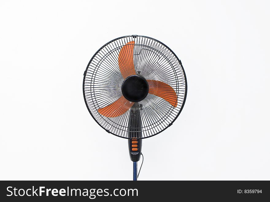 Black standing electrical office fan with three orange colored blades on a white background