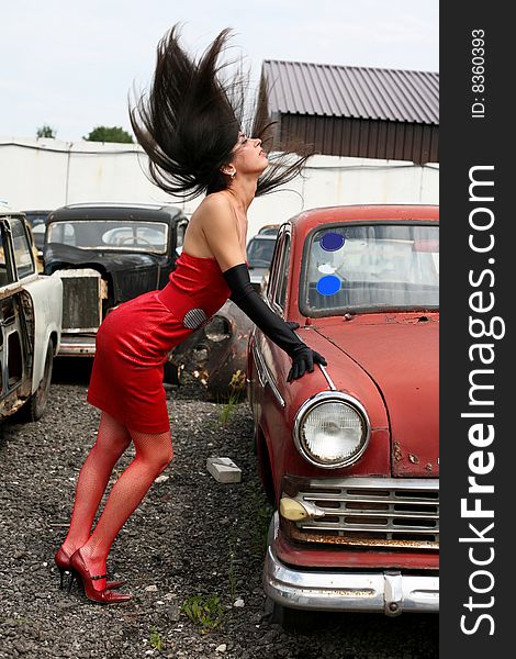 Girl with flapping hairs beside retro car