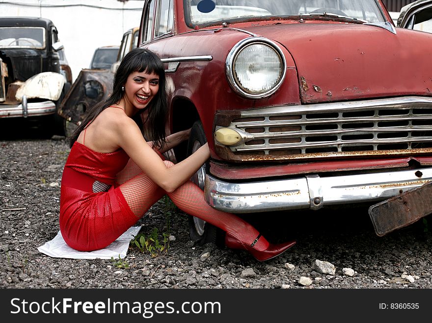 Girl beside retro car under construction to wheel. Girl beside retro car under construction to wheel