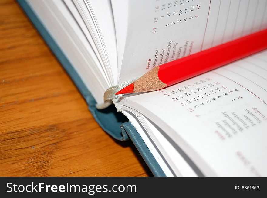 Open diary with red pencil on writing table