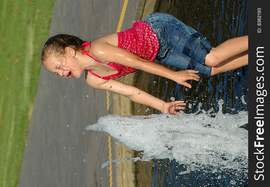 Girl with an expressive face playing in a water fountain. Girl with an expressive face playing in a water fountain