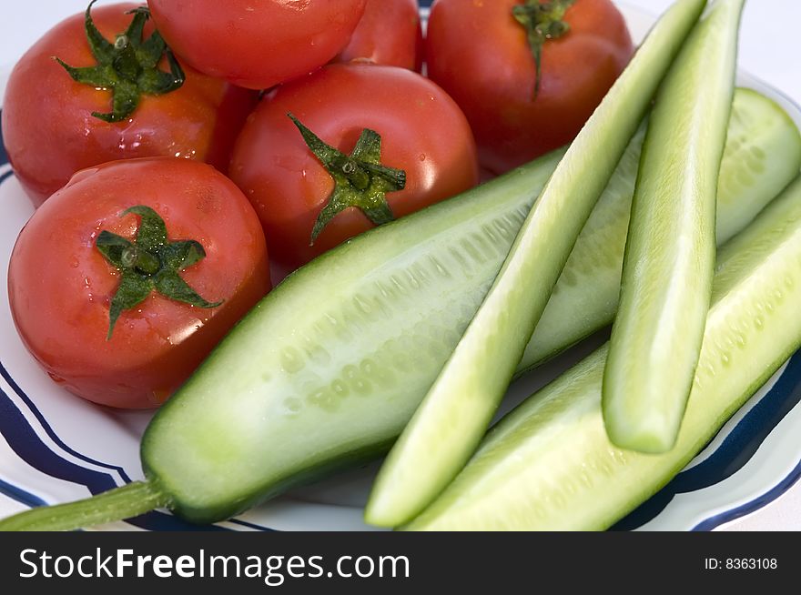 Tomato & cucumber on a plate over white background