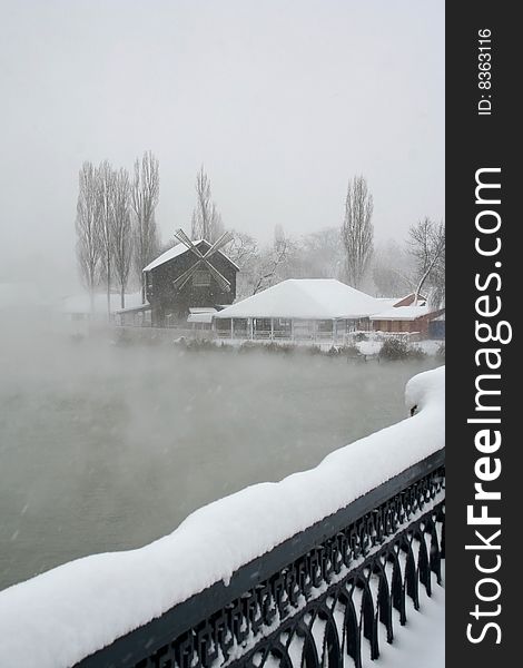 The Strong snow.The Tree and bulrushes in snow on river.The Type with bridge on mill and river. The Strong snow.The Tree and bulrushes in snow on river.The Type with bridge on mill and river.