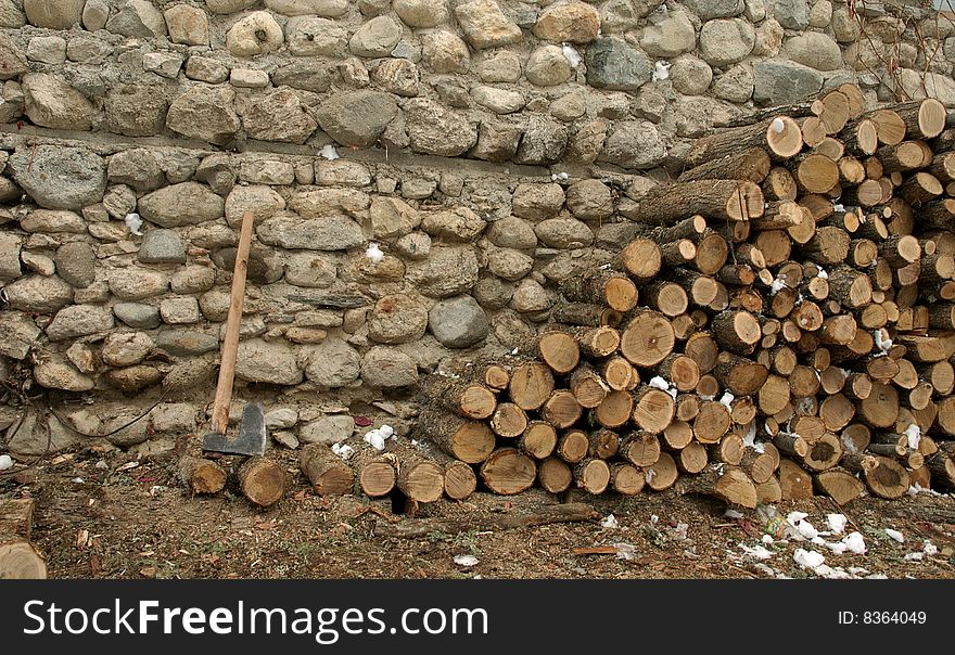 Fire wood and axe on a background of a stone wall