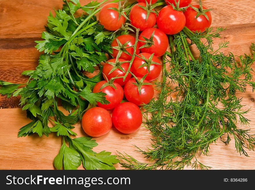 Tomatoes,  dill and parsley on a kitchen wooden board. Tomatoes,  dill and parsley on a kitchen wooden board