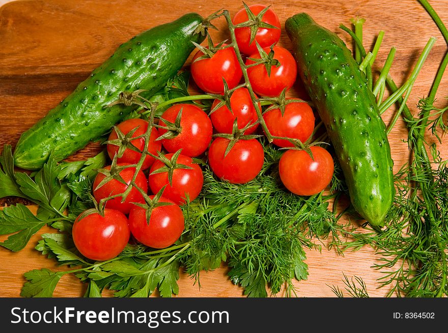 Tomatoes, cucumbers, dill and parsley on a kitchen wooden board. Tomatoes, cucumbers, dill and parsley on a kitchen wooden board