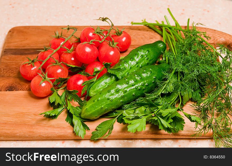 Tomatoes, cucumbers, dill and parsley on a kitchen wooden board. Tomatoes, cucumbers, dill and parsley on a kitchen wooden board