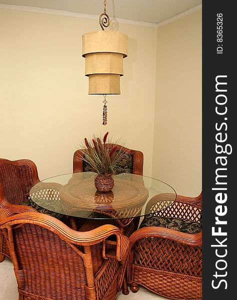 A dining room is decorated with whicker furniture and a unique light fixture.