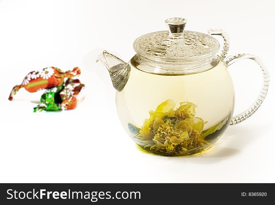 Clear teapot with a  flower tea and a beautiful flower in it. Clear teapot with a  flower tea and a beautiful flower in it