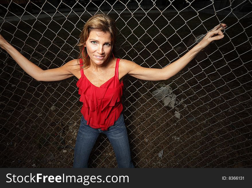 Beautiful woman posing on a fence. Beautiful woman posing on a fence