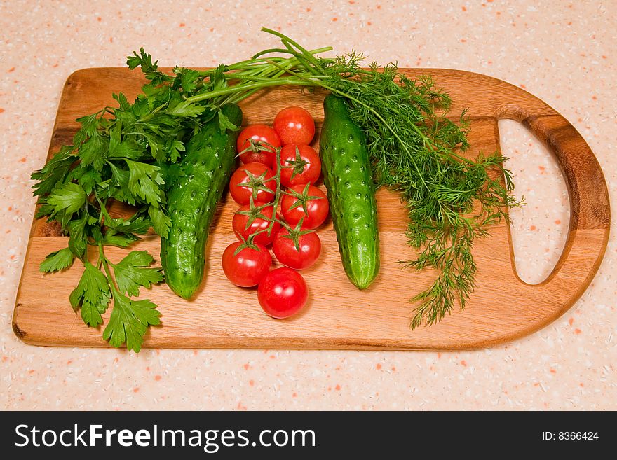 Tomatoes, cucumbers,  dill and parsley on a kitchen wooden board. Tomatoes, cucumbers,  dill and parsley on a kitchen wooden board