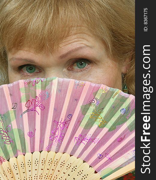 Woman face with green eyes is closed fan. Woman face with green eyes is closed fan