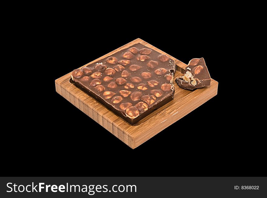 The hazelnut chocolate wooden plate on a black background