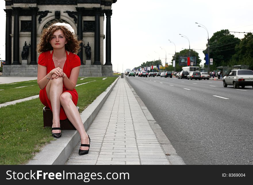 Girl sit atop in vintage suitcase in city. Girl sit atop in vintage suitcase in city