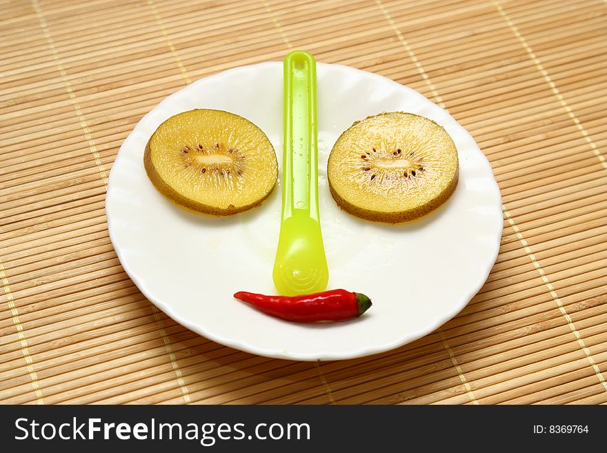 Smiling face(compose with golden kiwis,spoon and chili peppers)