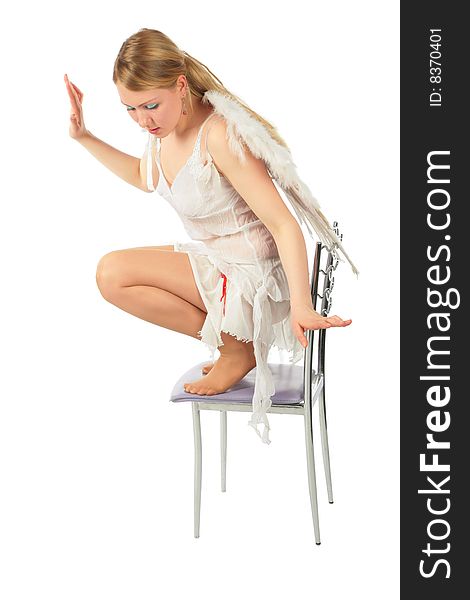 Girl in angel's costume squats on chair on white background