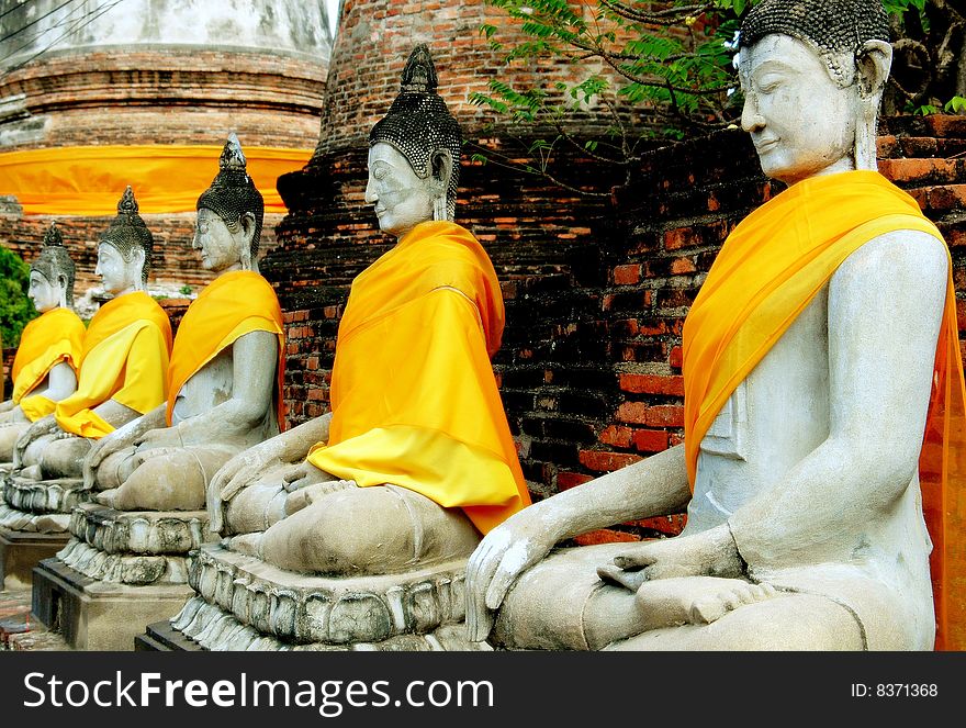 A row of seated Buddhas covered with silk saffron-coloured robes in the cloister gallery at Wat Yah Chai Mongkhon in Ayutthaya, Thailand - Lee Snider Photo Images. A row of seated Buddhas covered with silk saffron-coloured robes in the cloister gallery at Wat Yah Chai Mongkhon in Ayutthaya, Thailand - Lee Snider Photo Images.