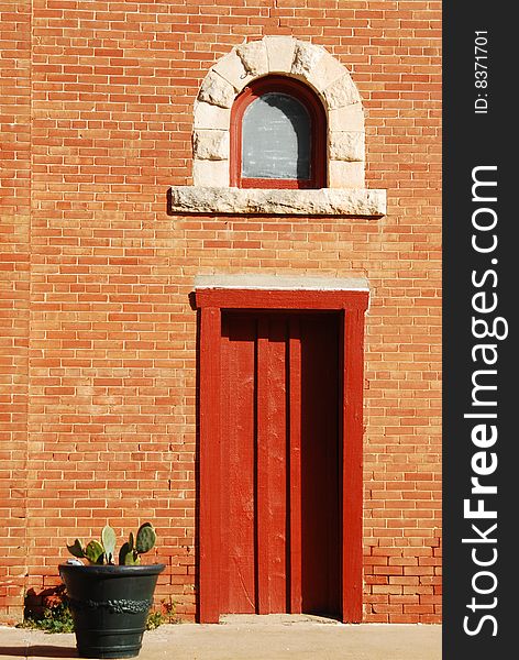 Rust door on brick building with cactus