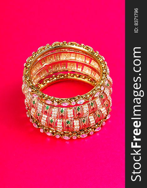 Golden bracelets looking great on colored background.