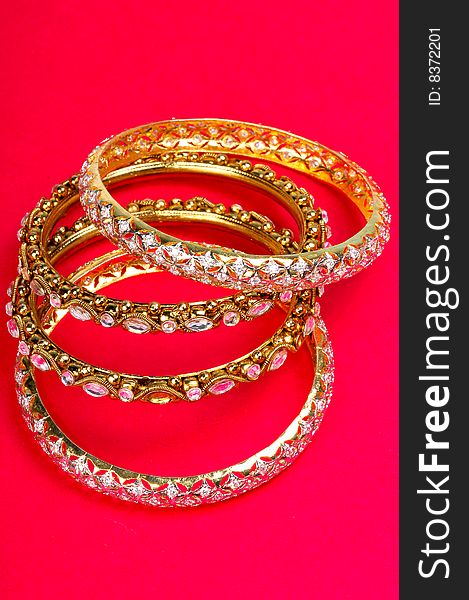 Golden bracelets isolated on colored background.