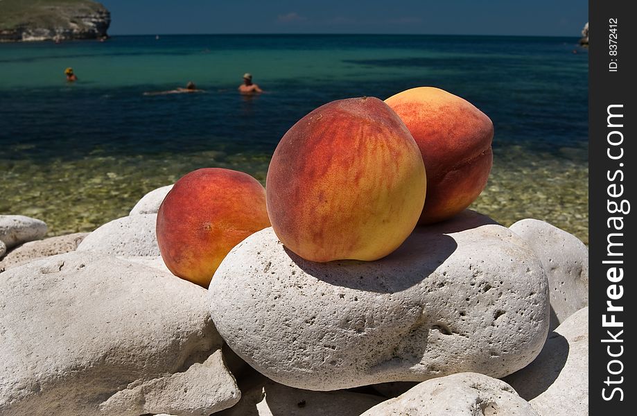 Tasty peaches are lying on the big sea stones near the sea. Tasty peaches are lying on the big sea stones near the sea