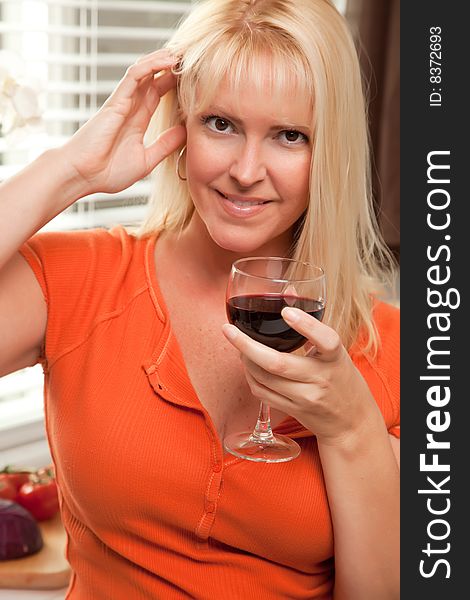 Attractive Blond with a Glass of Wine in the Kitchen