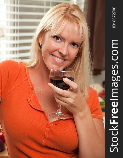 Attractive Blond with a Glass of Wine in the Kitchen