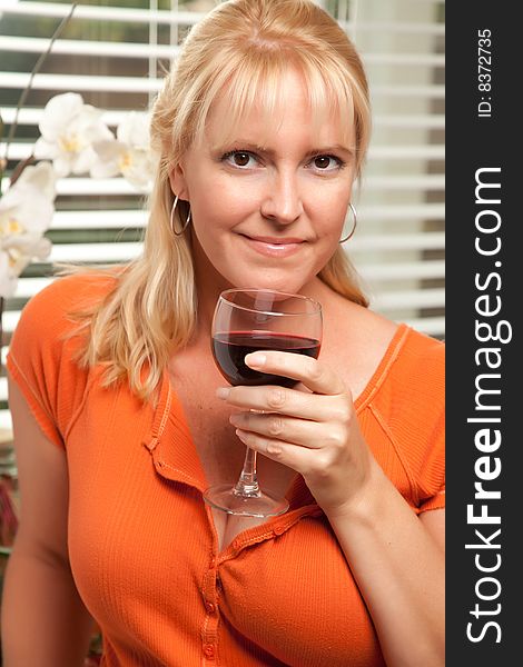 Attractive Blond with a Glass of Wine in the Kitchen