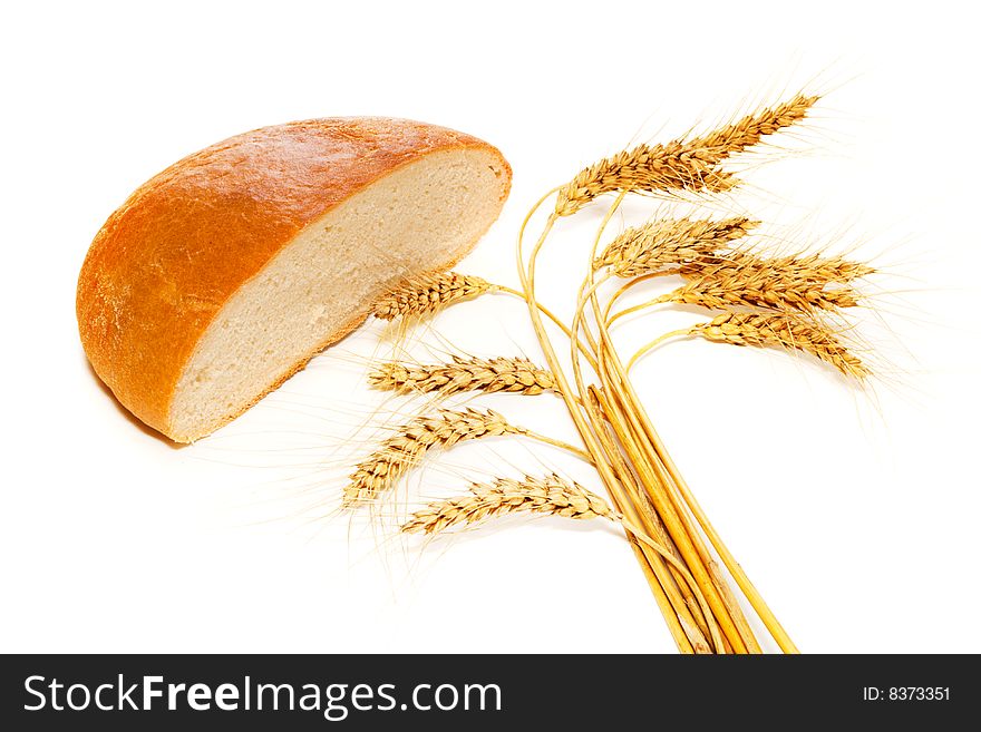 Half bread loaf and wheat spikes beside it, isolated. Half bread loaf and wheat spikes beside it, isolated