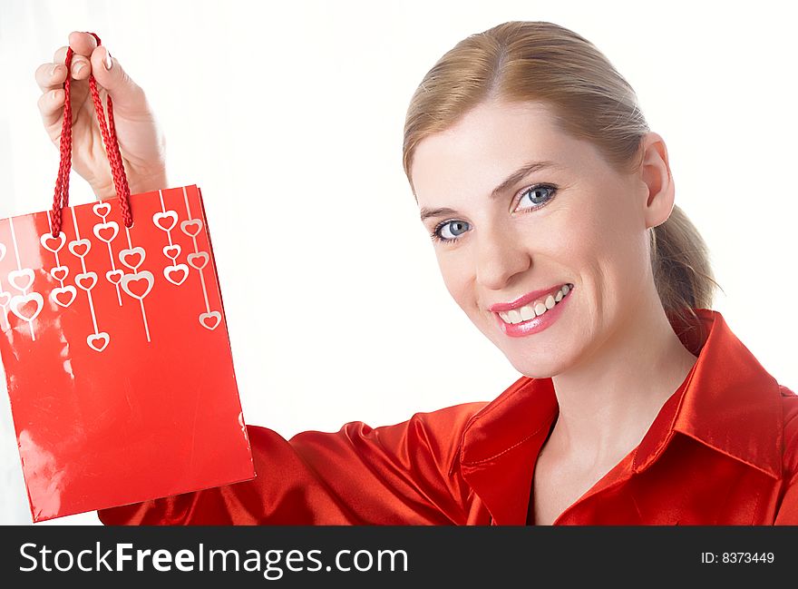 The beautiful girl in red with a gift package in hands