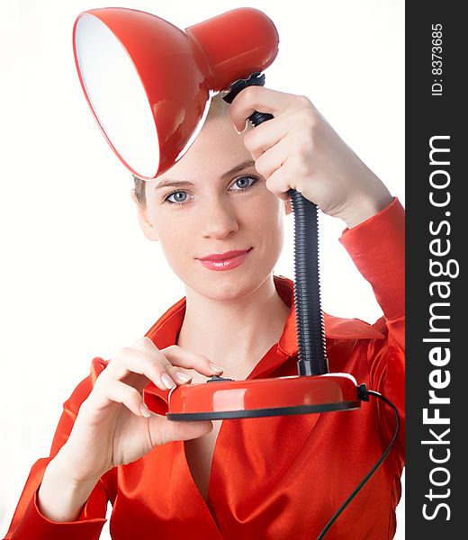 The beautiful girl in red holds a desk lamp in hands