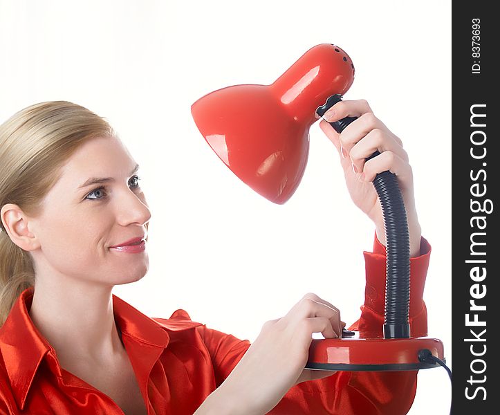 The beautiful girl in red holds a desk lamp in hands