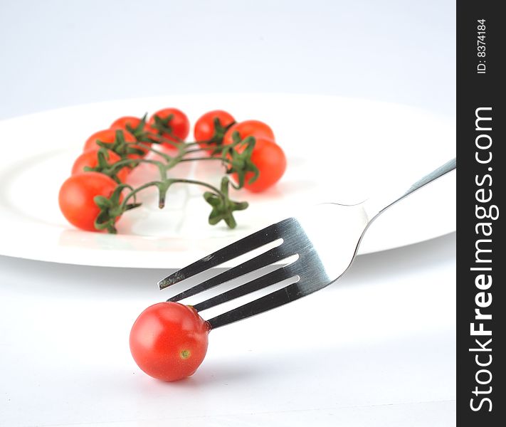 White background of the fork and small tomatoes