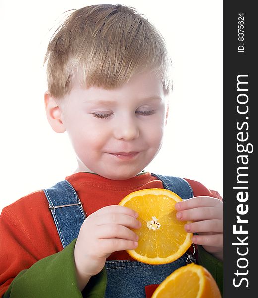 The small beautiful boy eats an orange. The small beautiful boy eats an orange