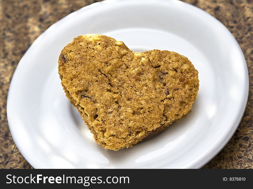 Heart shaped oatmeal raisin cookie on white plate