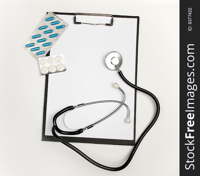 Medical clipboard, stethoscope and pills