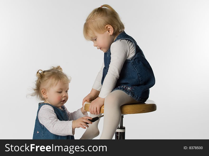 Two young girls playing on a stool.  White background.