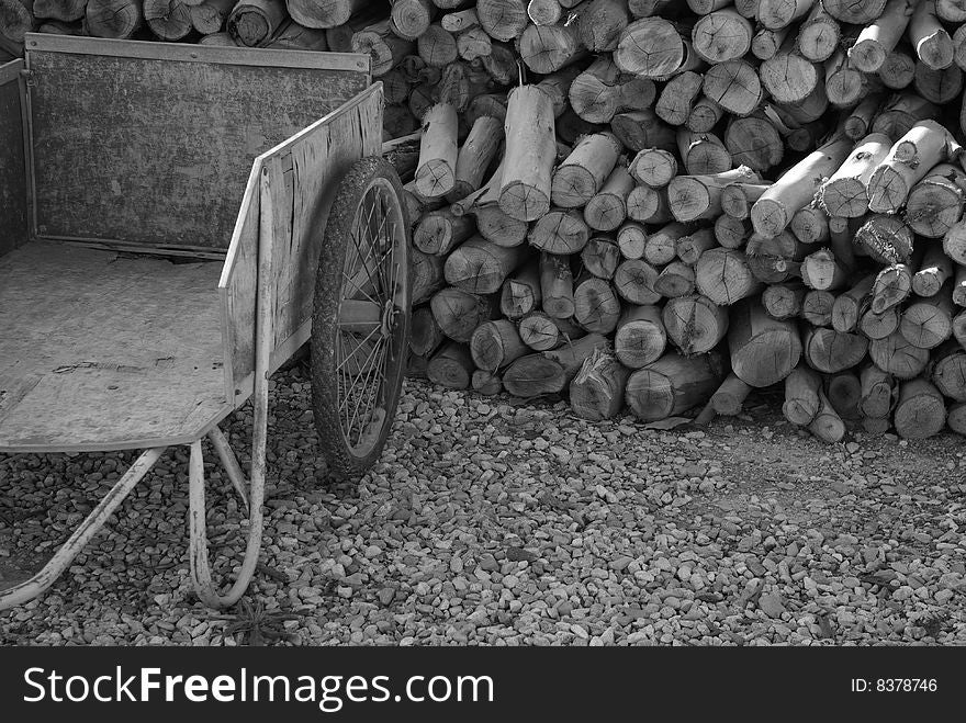 Old cart and stack of firewood on gravel path. Old cart and stack of firewood on gravel path
