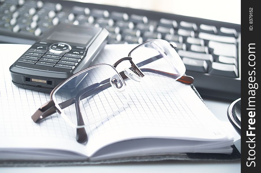 The opened notebook,  glasses and keyboard. The opened notebook,  glasses and keyboard