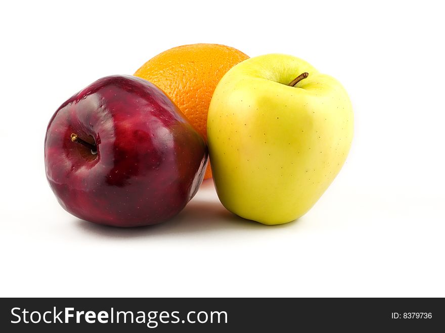 A red apple, yellow apple, and orange isolated on white background with copy space. A red apple, yellow apple, and orange isolated on white background with copy space