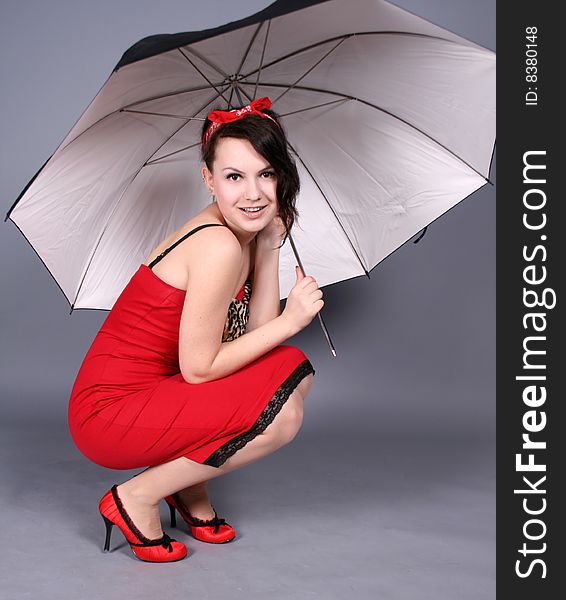 Pin-up girl sitting under umbrella in studio