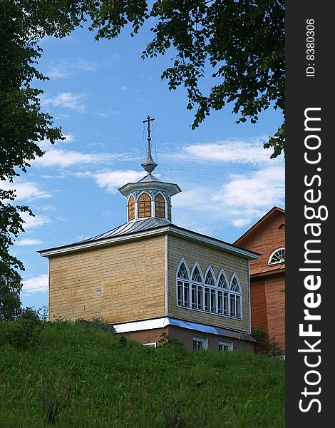 Orthodox chapel in leaves border. Blue sky background with clouds
